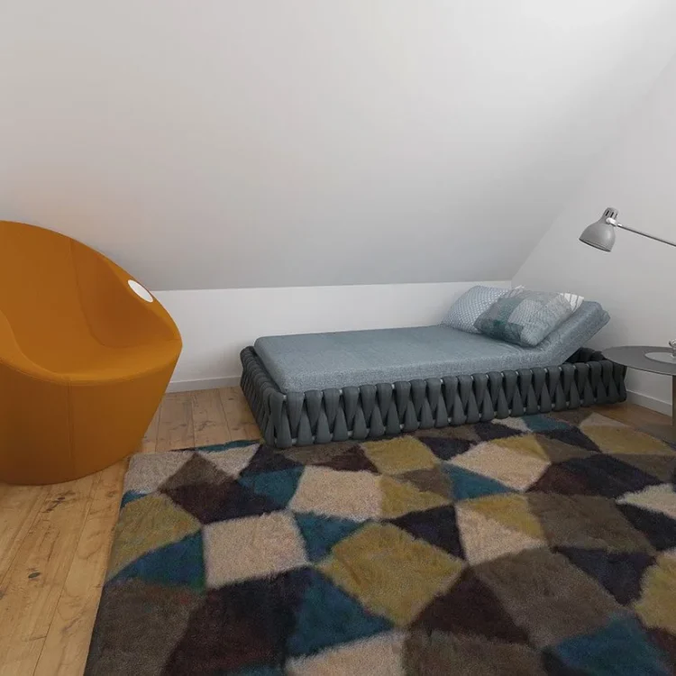 Kinderzimmer mit orangem Sessel, blaugrauem Bett und buntem geometrischem Teppich auf Holzboden
