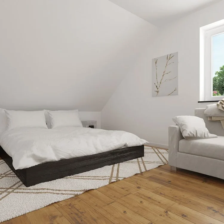 Modernes Schlafzimmer mit dunklem Bett, weißer Bettwäsche, beigem Sessel und Holzboden unter Dachschräge