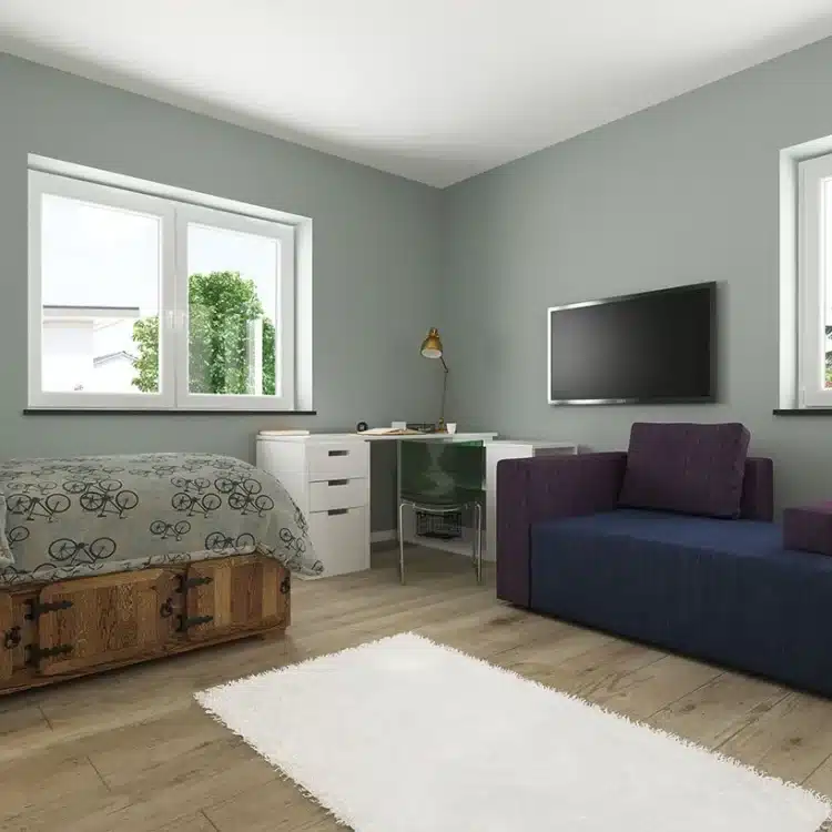 Modernes Kinderzimmer mit hellgrauen Wänden, blauem Sessel, Holzbett mit gemusterter Bettwäsche und weißem Schreibtisch